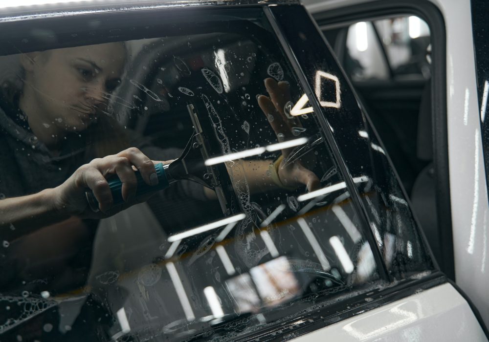 Experienced service station employee fixing PPF on car glass